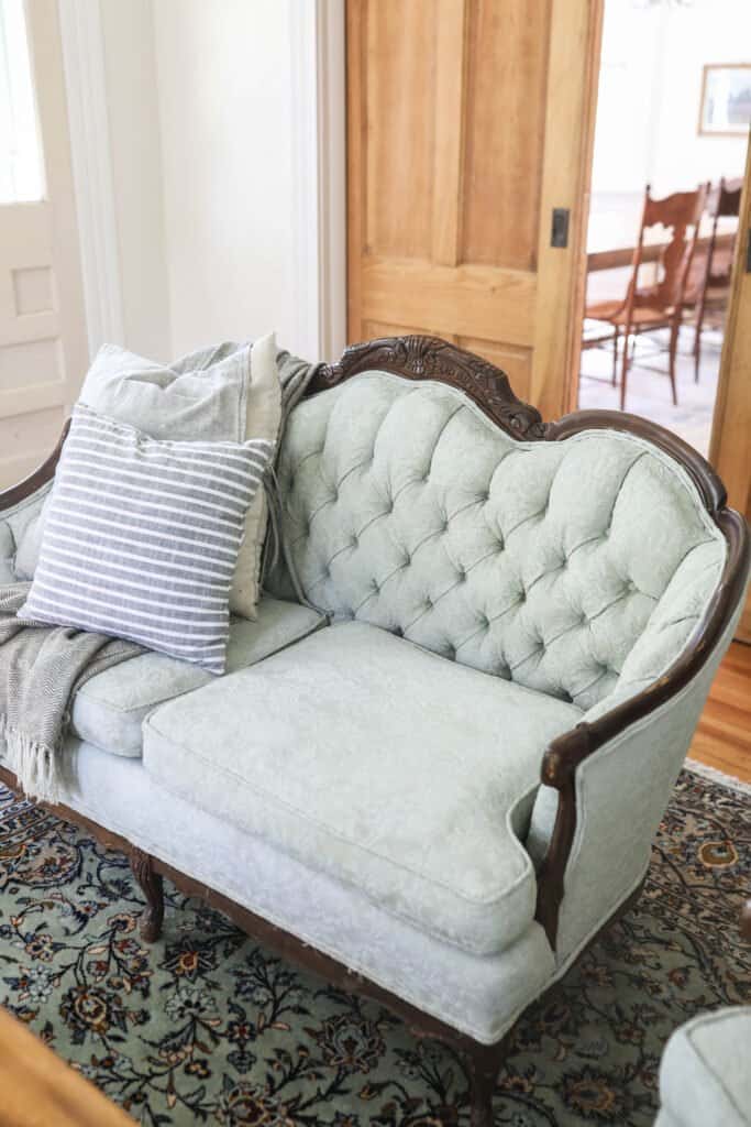 victorian loveseat chalk painted soft green in a living room with pillows