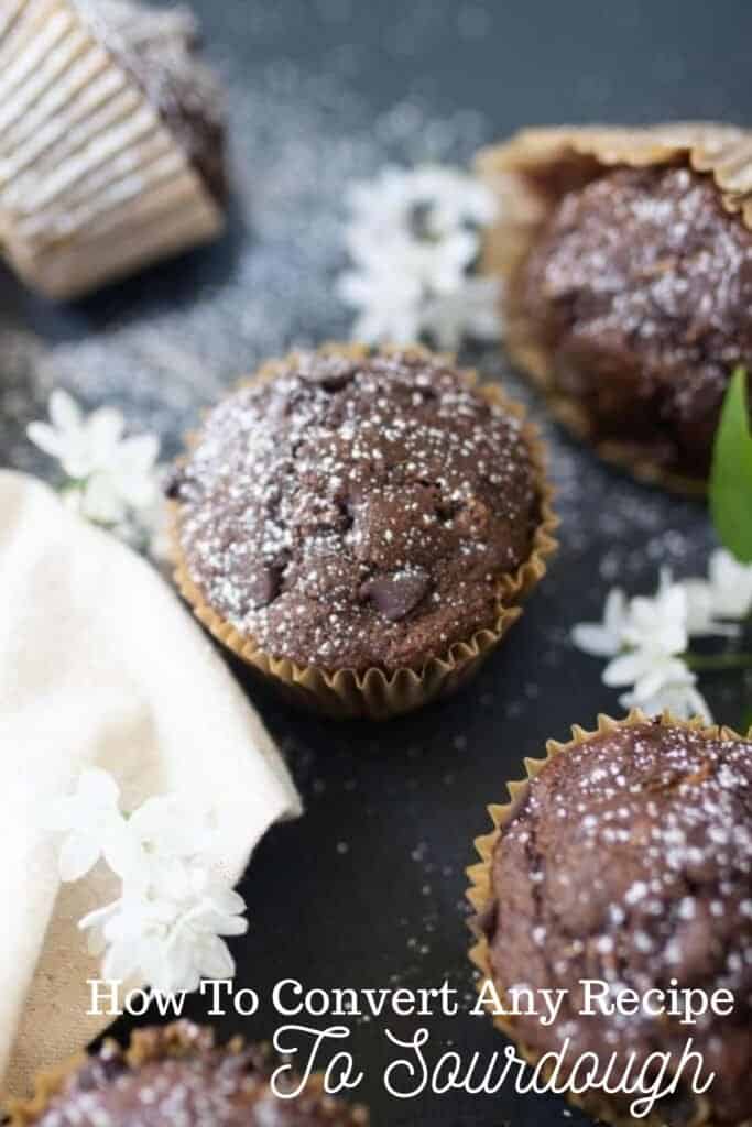 sourdough chocolate zucchini muffins on a black countertop with flowers