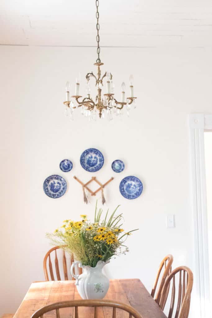 blue and white antique plates hanging on a wall above a farmhouse table