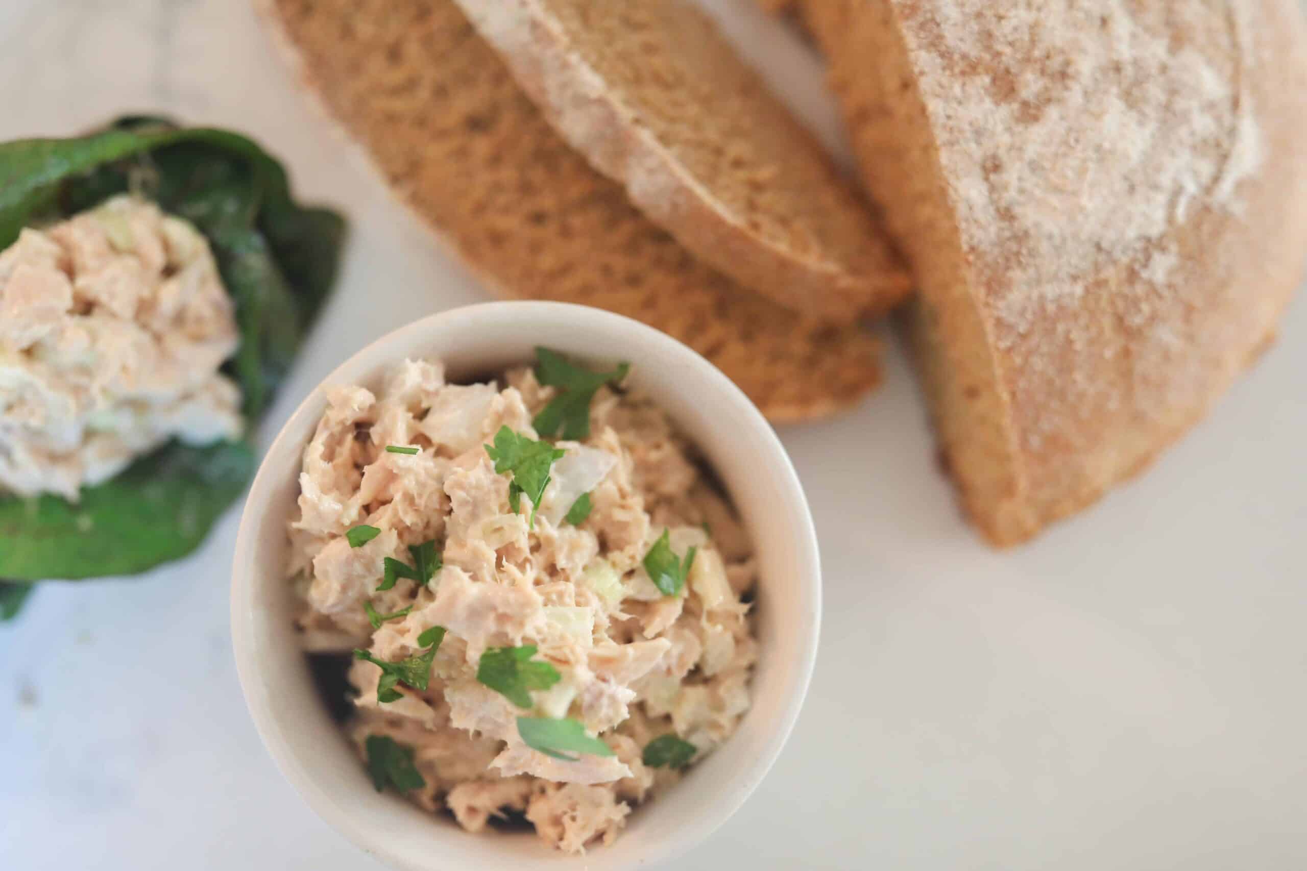 healthy tuna salad in a white bowl with a loaf of einkorn bread