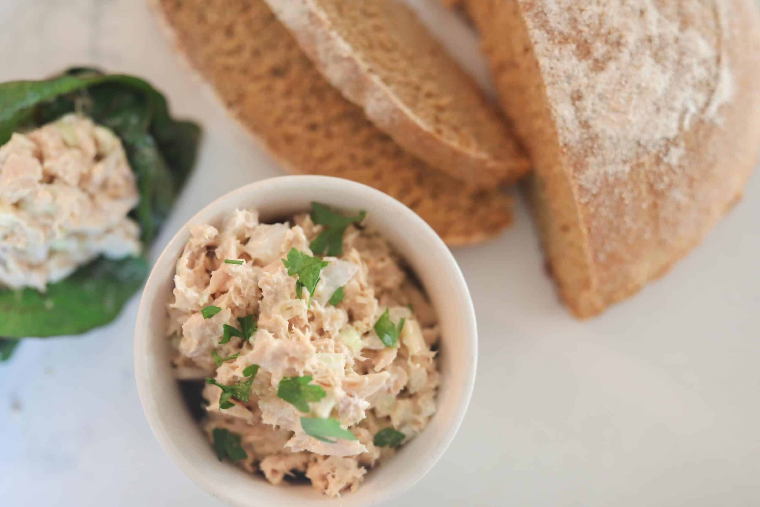 healthy tuna salad in a white bowl with a loaf of einkorn bread