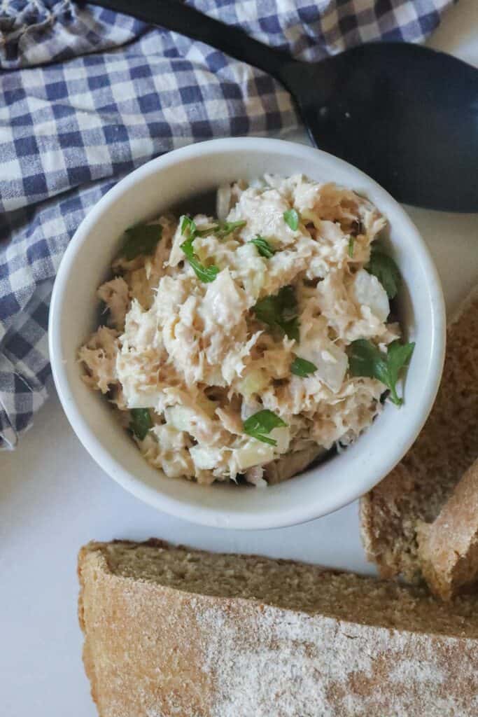 healthy tuna salad in a white bowl with a blue and white towel in the background