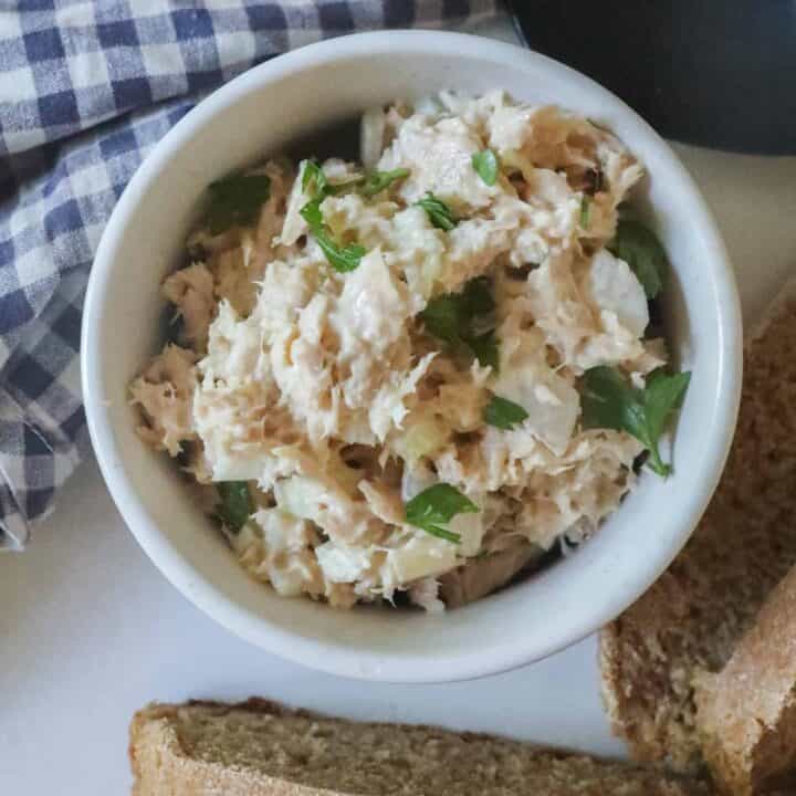 healthy tuna salad in a white bowl with a blue and white towel in the background