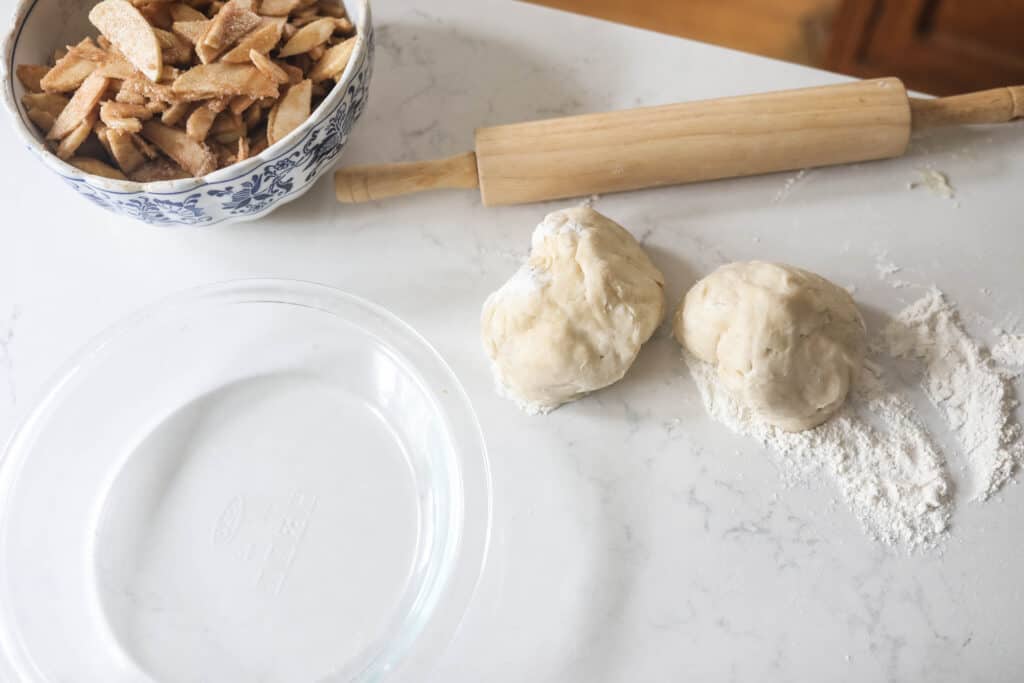 sourdough pie crust in two balls with a glass pie plate to the let