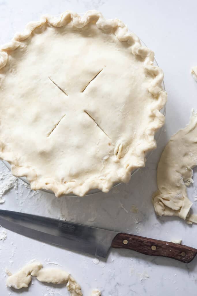 sourdough apple pie ready to be baked, the edges are crimped and slits mad e in the top