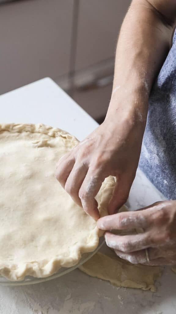 women crimping the edges of an apple pie with sourdough crust