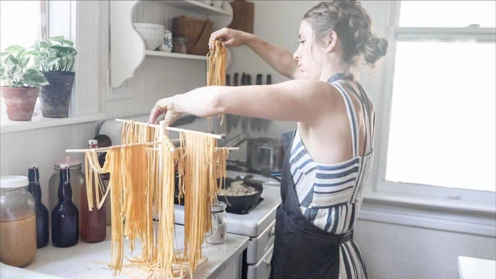 women placing homemade pasta from the pasta drying rack to a pot of boiling water