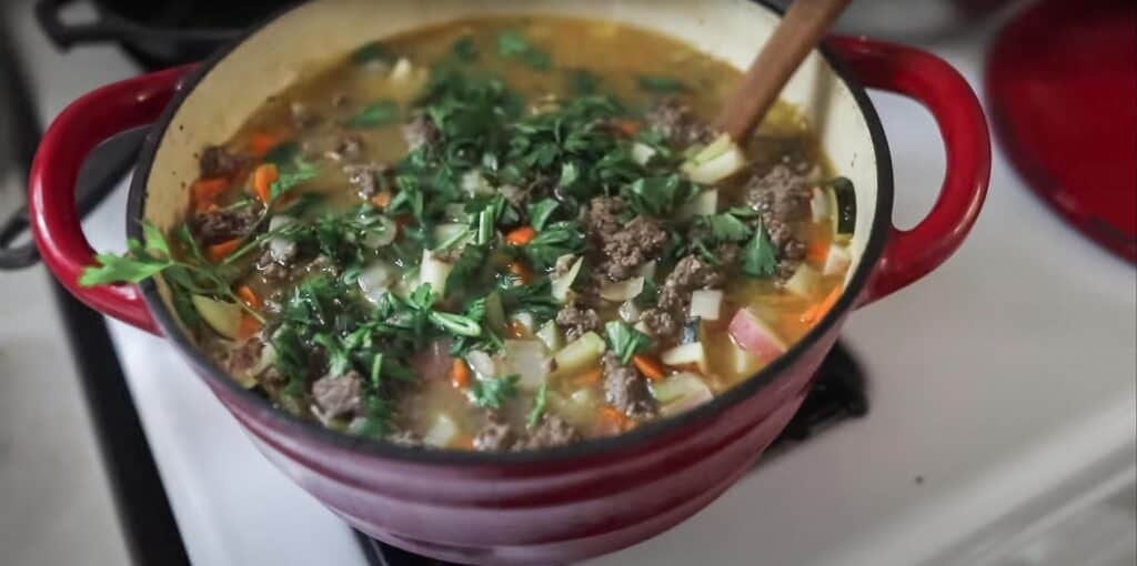 garden soup full of fresh veggies, potatoes, and fresh herbs in a chicken stock