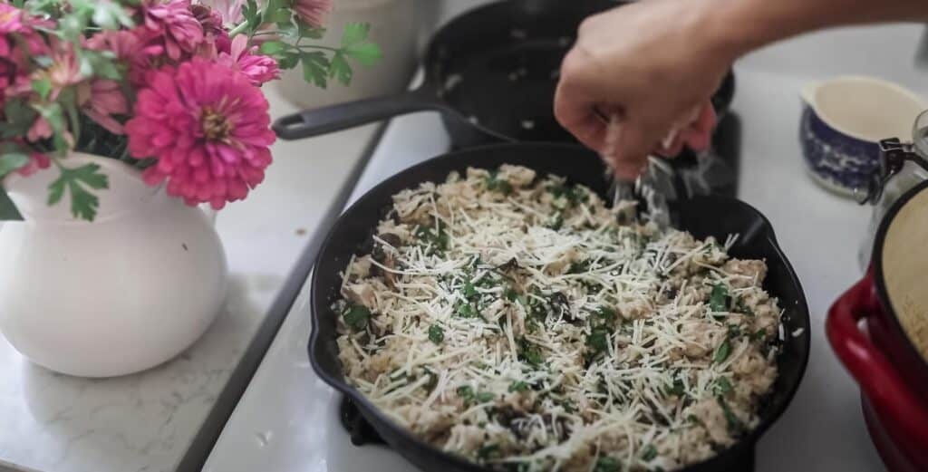 risotto in a cast iron skillet with chicken and herbs and topped with cheese