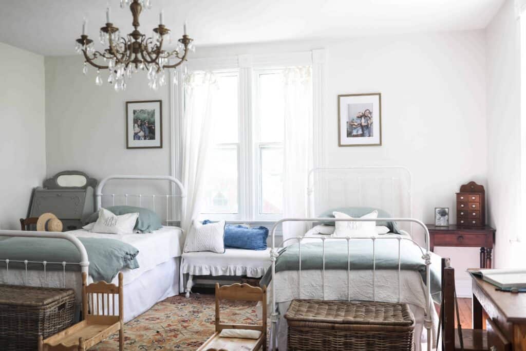 victorian farmhouse girls room with two twin beds and a gold chandelier