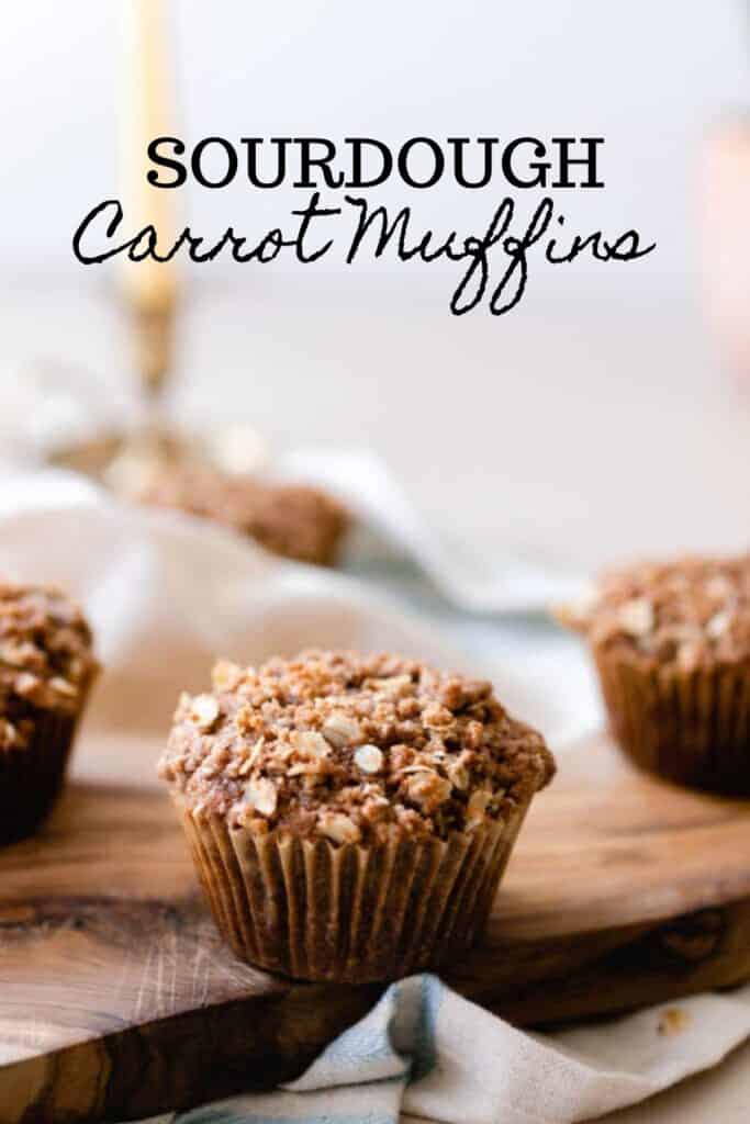 sourdough carrot muffin on wood cutting board with a napkin and candle stick in the background