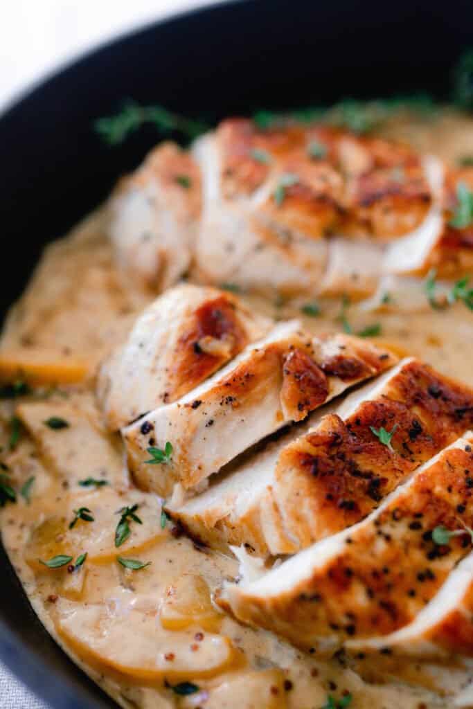 sliced chicken breasts on top of a creamy peach sauce