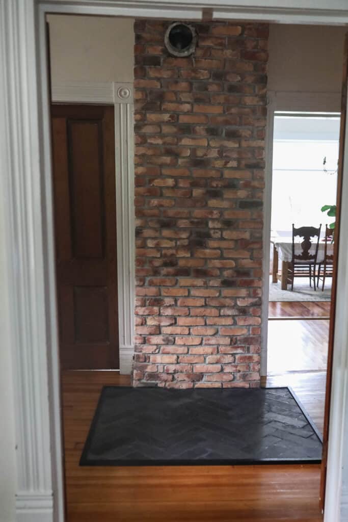 front view of a brick chimney with a DIY hearth pad made from slate in a herribone pattern