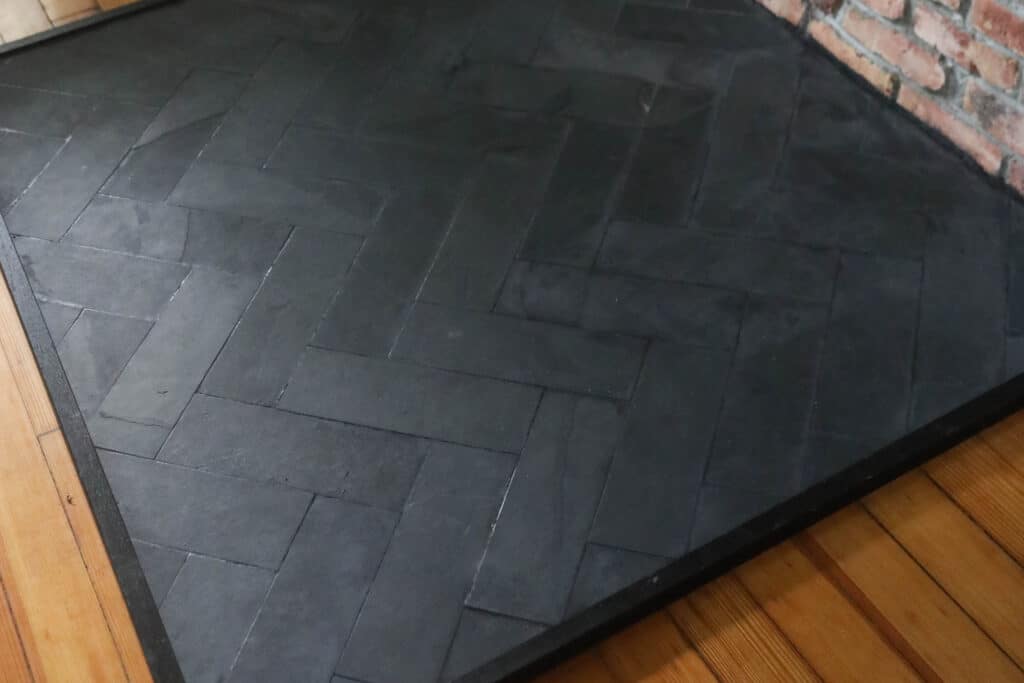 close up picture of a DIY hearth pad with slate tile in a herringbone pattern