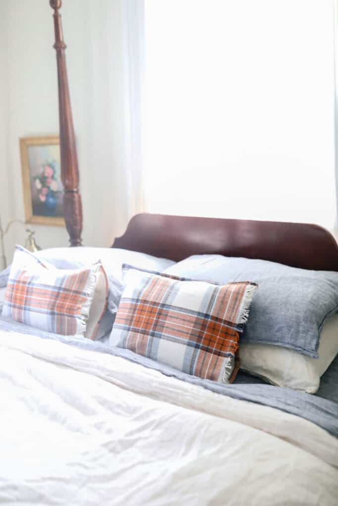 blue and orange plaid pillows on a bed with white and blue linen sheets