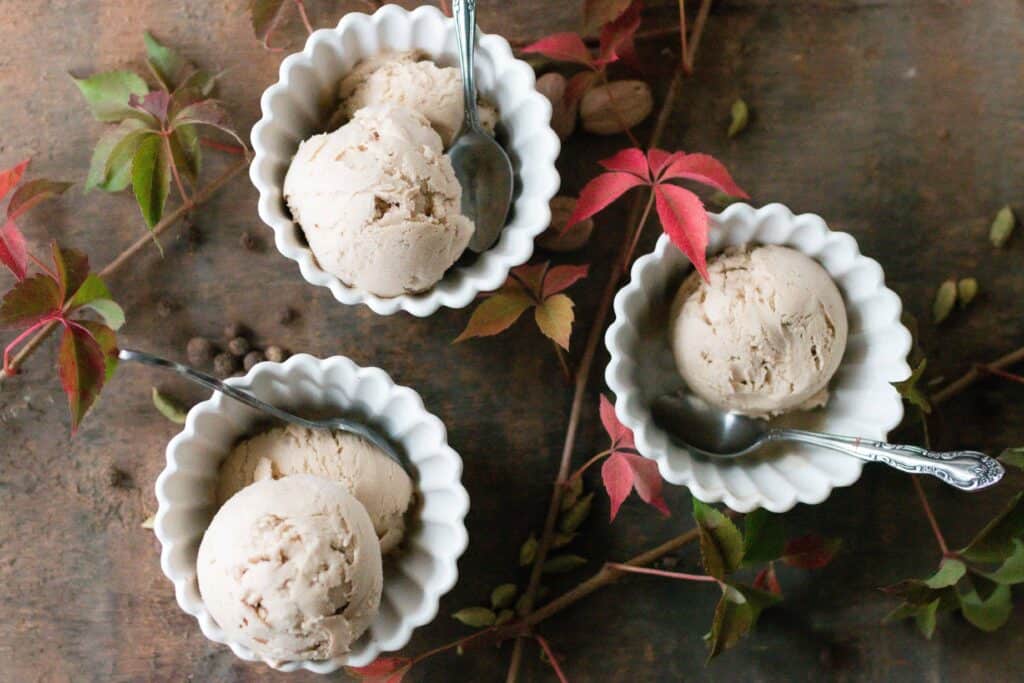 3 white bowls of chai ice cream on a wood table with fall leaves and spices 