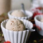 chai ice cream in white bowls with spoons. Red fall leaves are set on the table