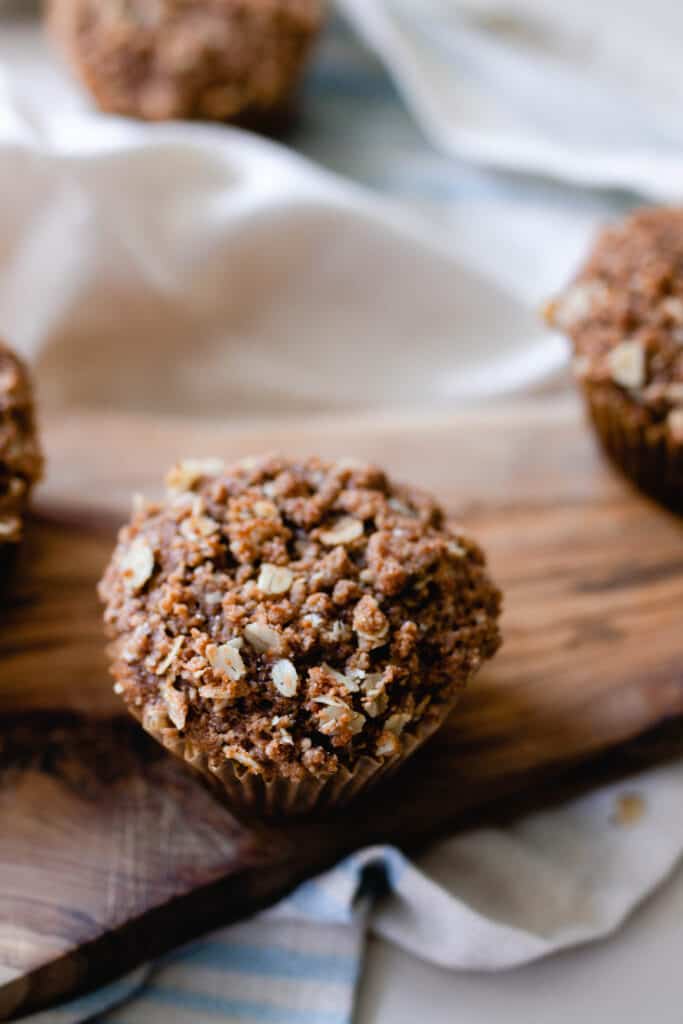 oat streusel on top of sourdough carrot cake muffin on a wood cutting board