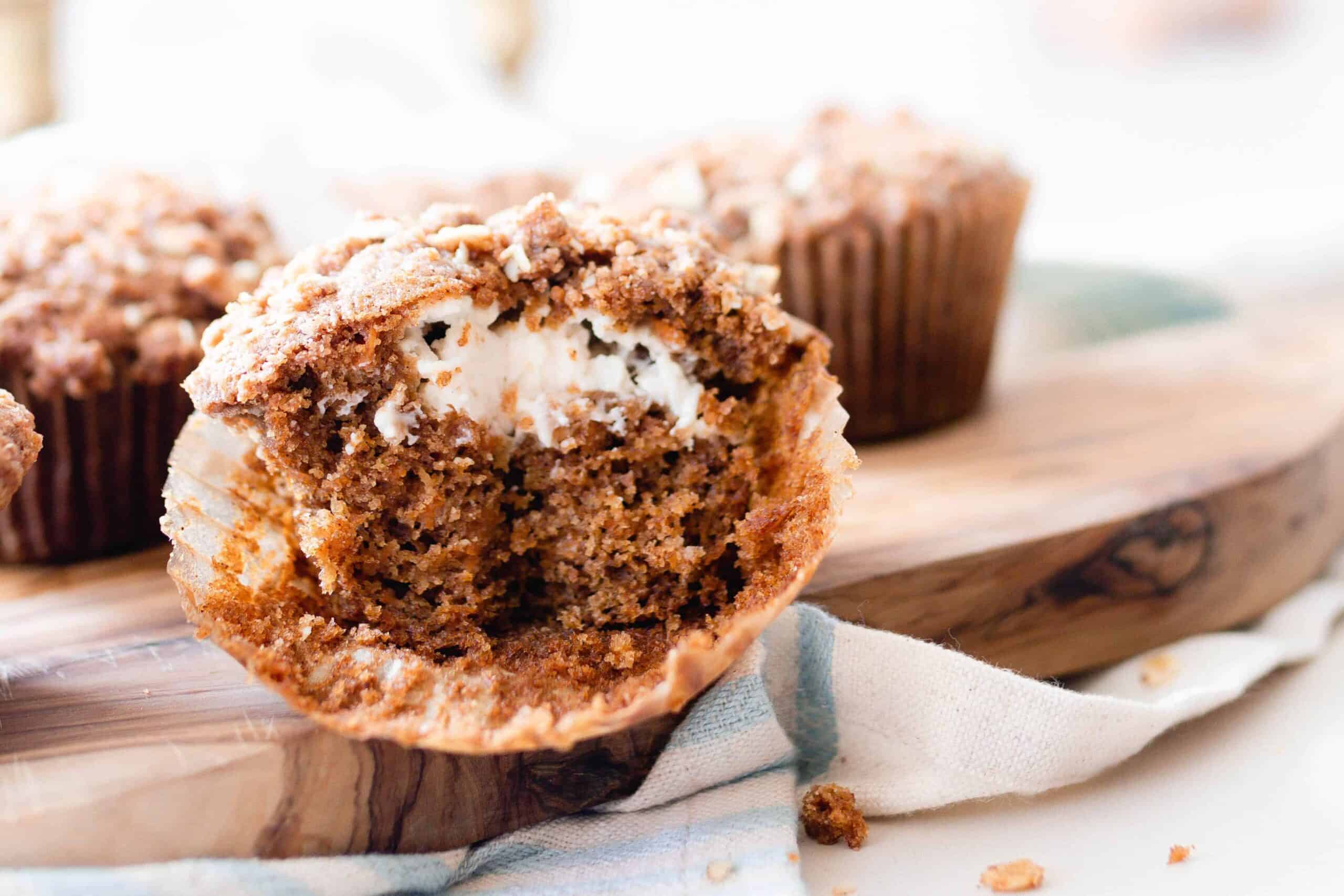 sourdough carrot muffin cut in half on a cutting board with more muffins in the background