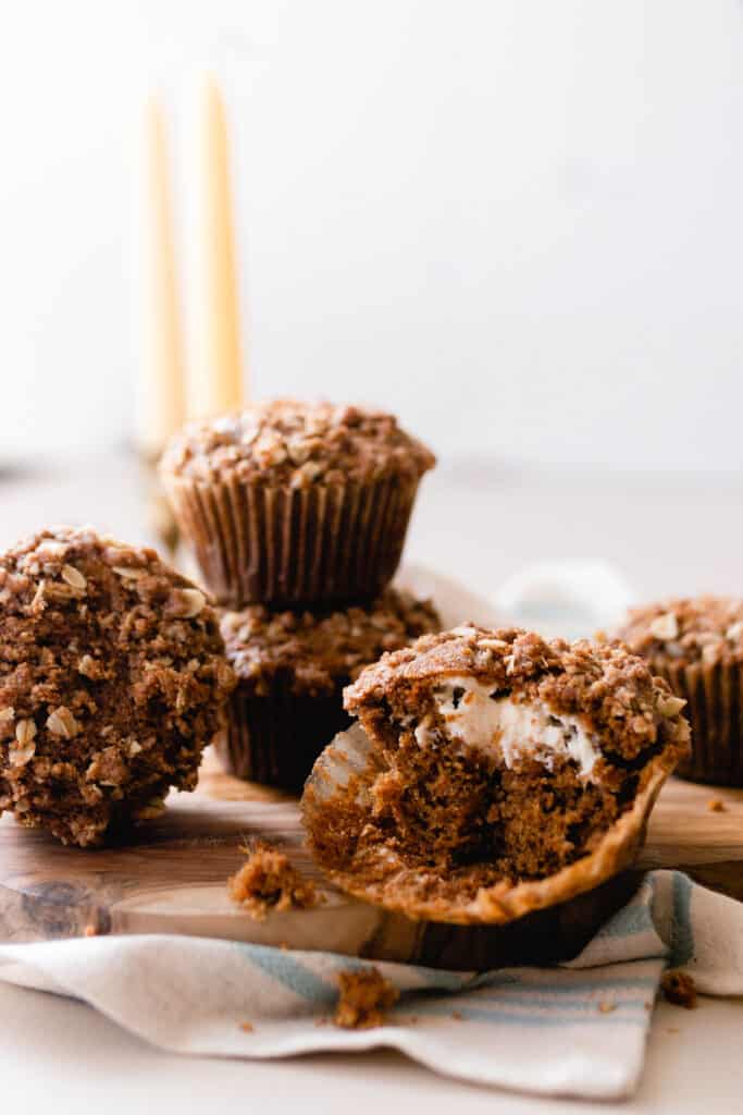 a sourdough carrot cake muffins cut in half on a wood cutting board with more muffins in the background