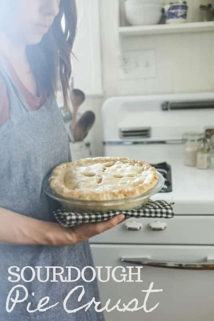 women wearing a pinafore apron taking an apple pie out of the oven