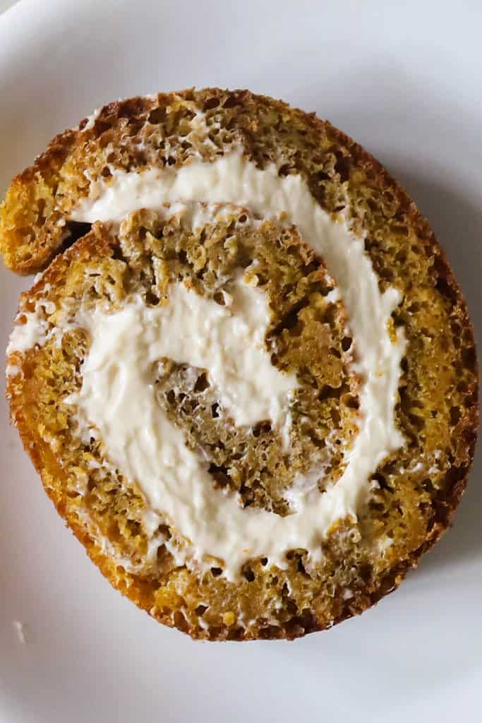 close up of a sourdough pumpkin roll with cream cheese filling on a white plate