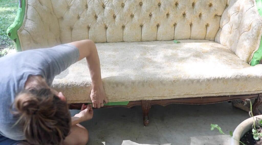 women placing painters tape on wood details of a couch