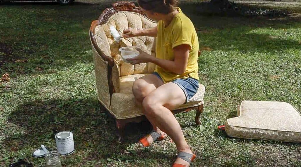 women wearing a yellow shirt chalk painting a victorian chair