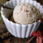 One white bowl with one scoop of chai ice cream with a spoon.