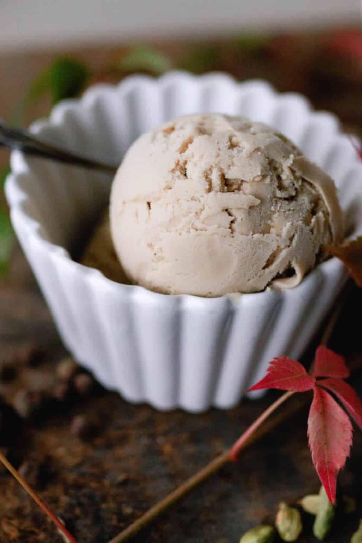 One white bowl with one scoop of chai ice cream with a spoon.
