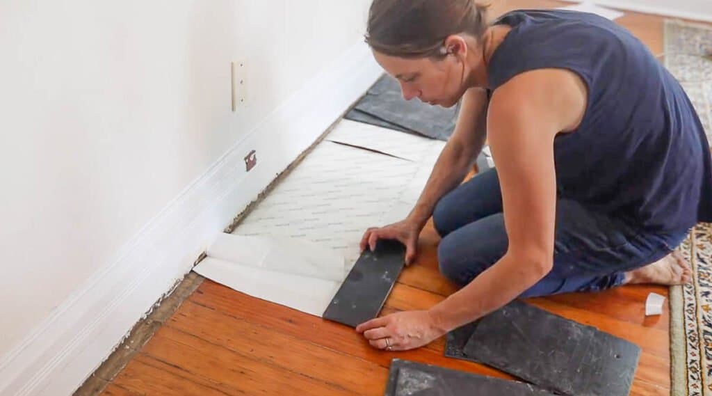 women laying slate tile on tile adhesive pad to make a hearth