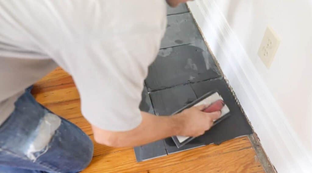 man grouting slate tile to make a fireplace hearth