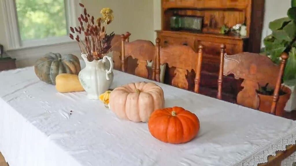pumpkins on a table with a white linen table cloth
