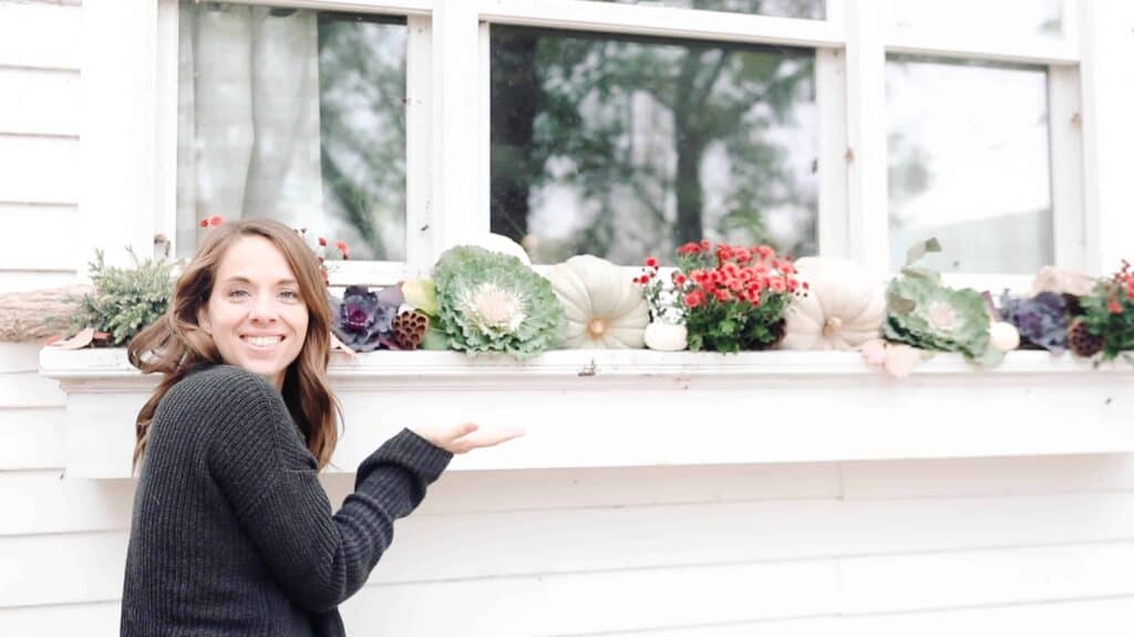 women standing next to a fall window box full of beautiful fall foliage