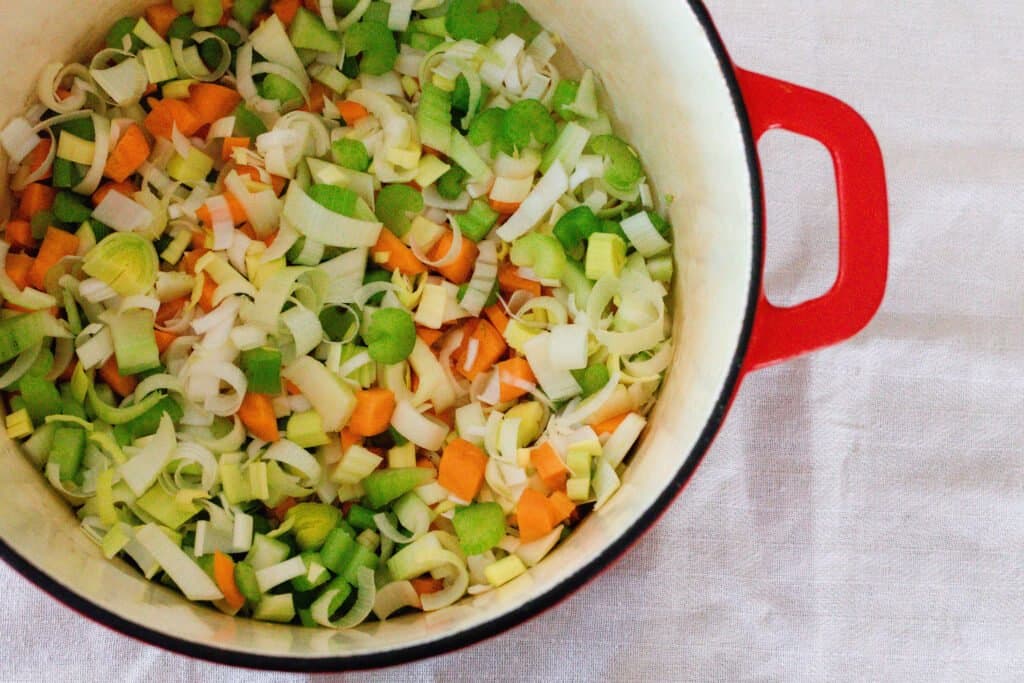 veggies in a red dutch oven to make soup