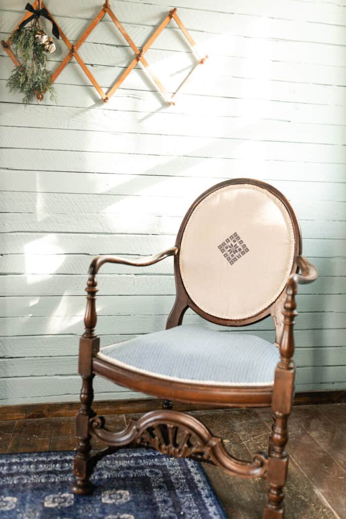 redone antique chair on a blue Turkish inspired rug with an accordion coat hanger hanging on the wall