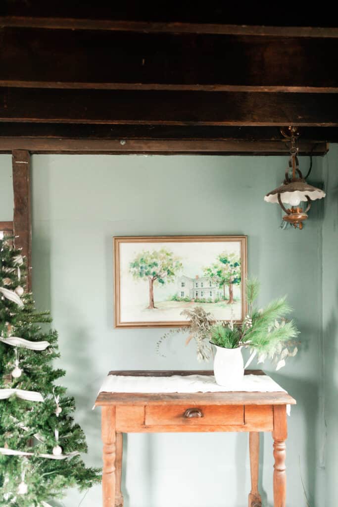 100 year old walnut table with a table runner. a water color picture hangs above it.