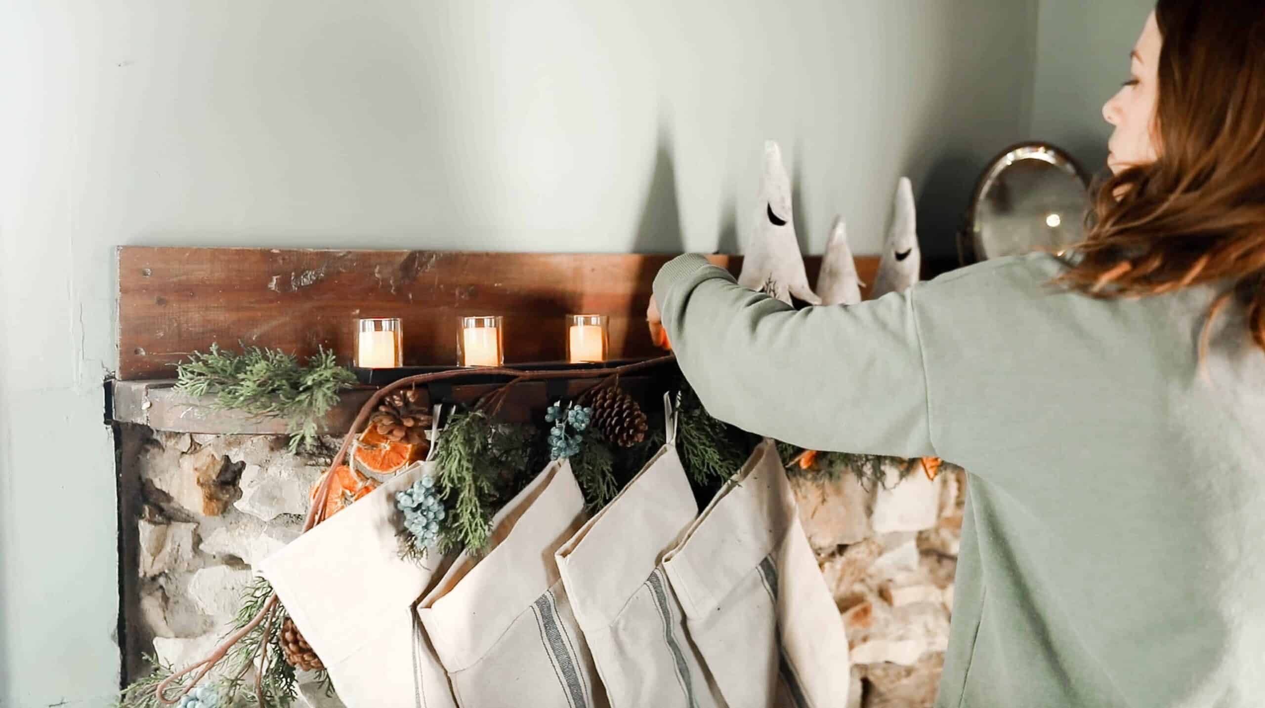 women hanging burlap stockings on a cottage stone mantle