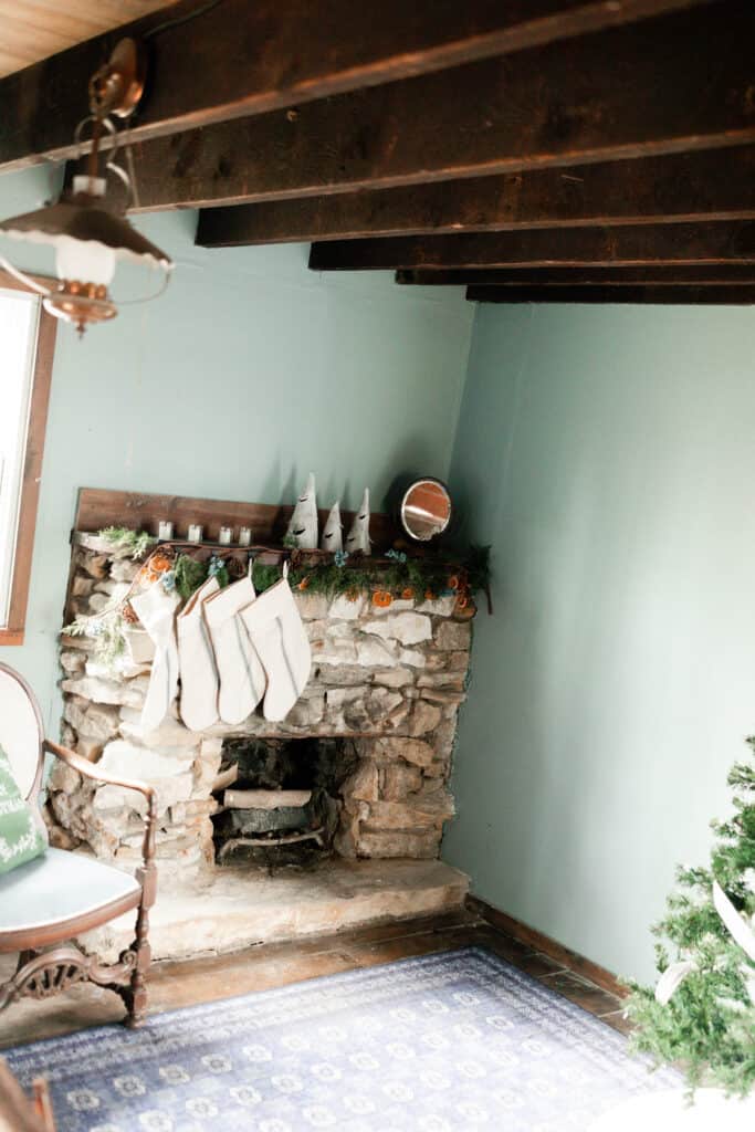 stone fireplace with a wood mantle decorated for a cottage Christmas with garland and burlap stockings