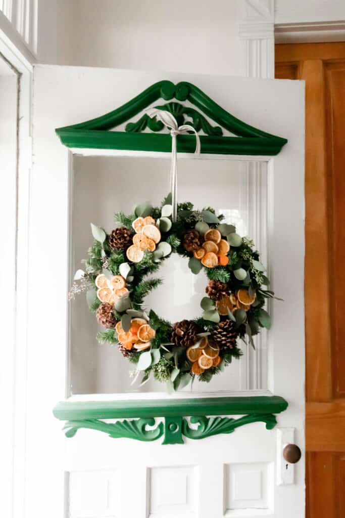 dried eucalyptus wreath with dried oranges and pinecones hanging on a vintage victorian door