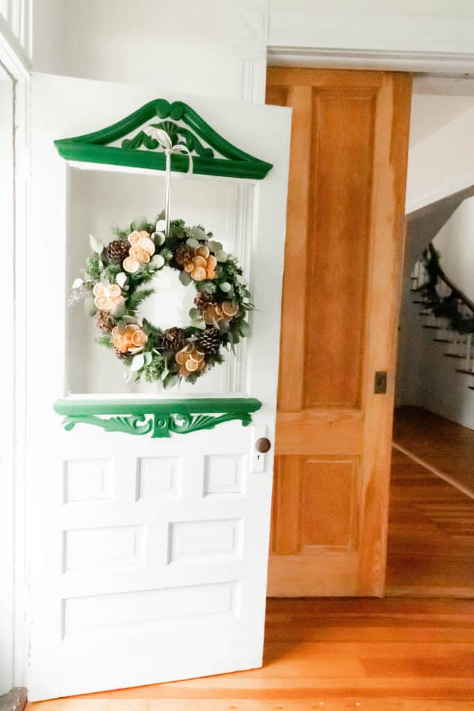 antique white and green door with a diy Christmas wreath hanging by ribbon