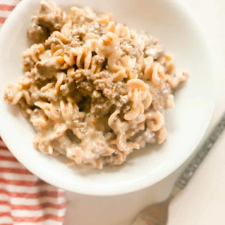 healthy homemade hamburger helper in a white bowl with a red and white stripped towel and a fork
