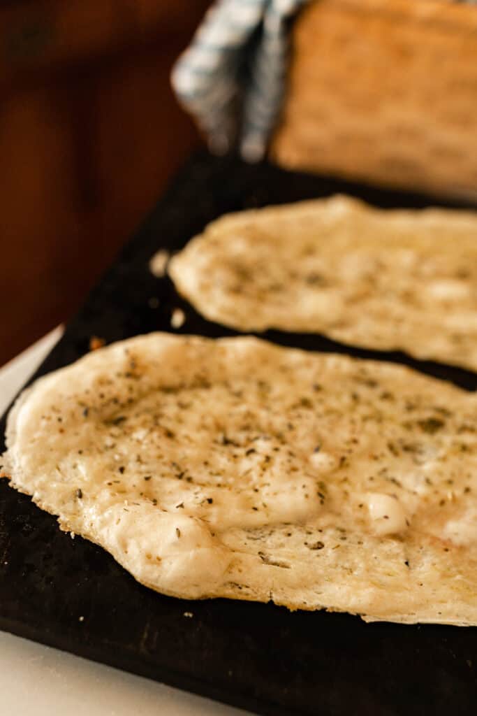 sourdough flat bread on a pizza stone with herbs