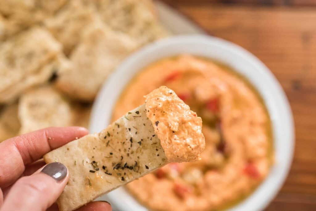 sourdough flat bread dipped into a bowl of roasted red pepper hummus