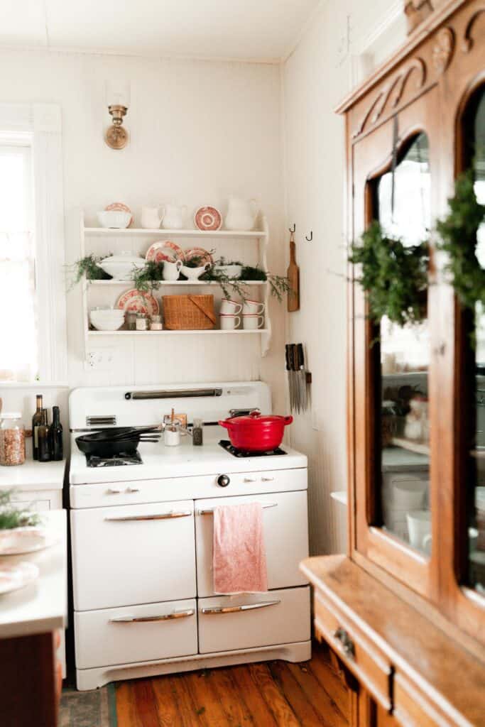 antique stove with pops of red decor on the open shelves