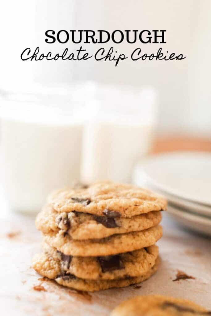 sourdough chocolate chip cookies stacked up with glasses of milk in the background