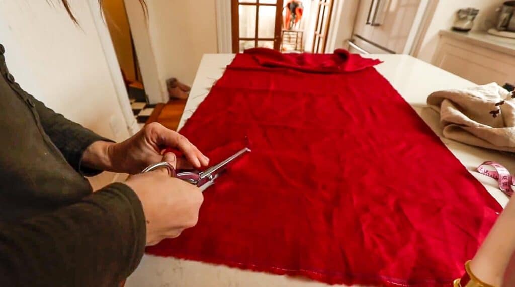 women cutting red linen fabric