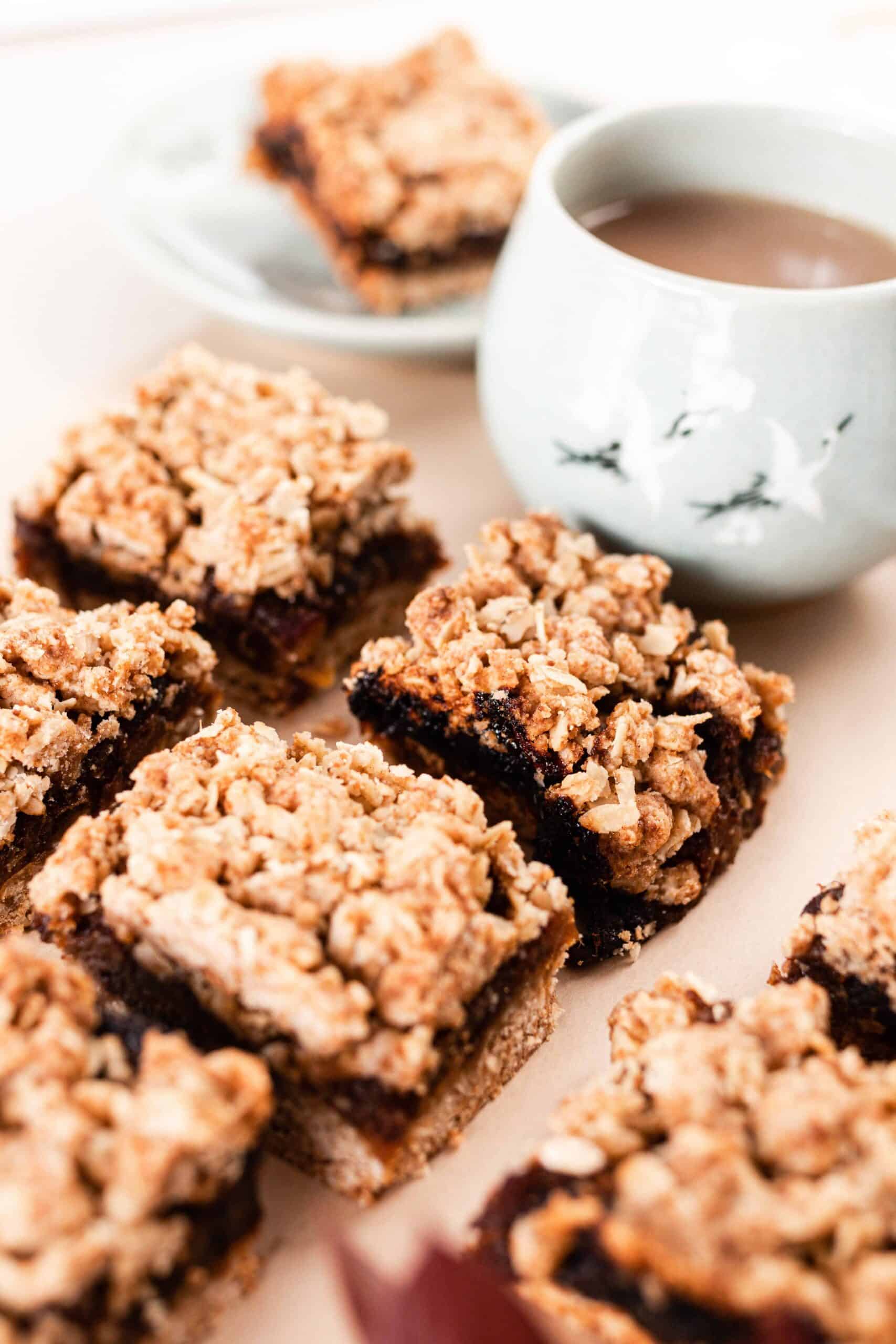 date squares on parchment paper with a mug of coffee behind