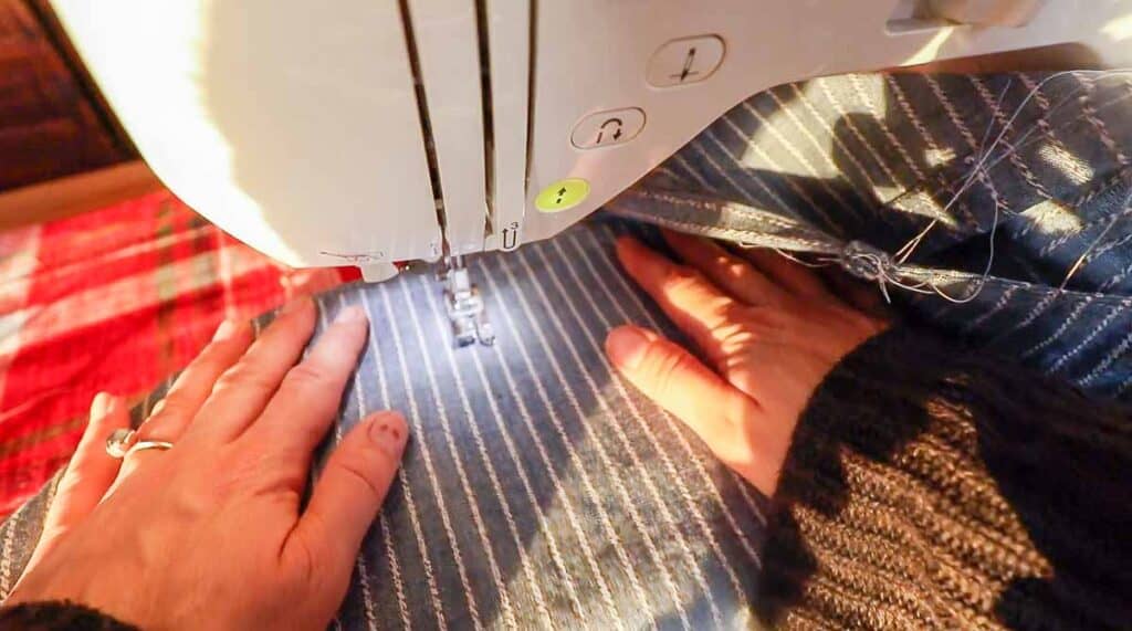 a women sewing a top stitch down the center of a pocket on a half apron to create two smaller pockets,.