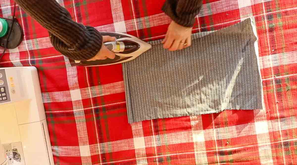 women folding over fabric and ironing a hem over to create a pocket.